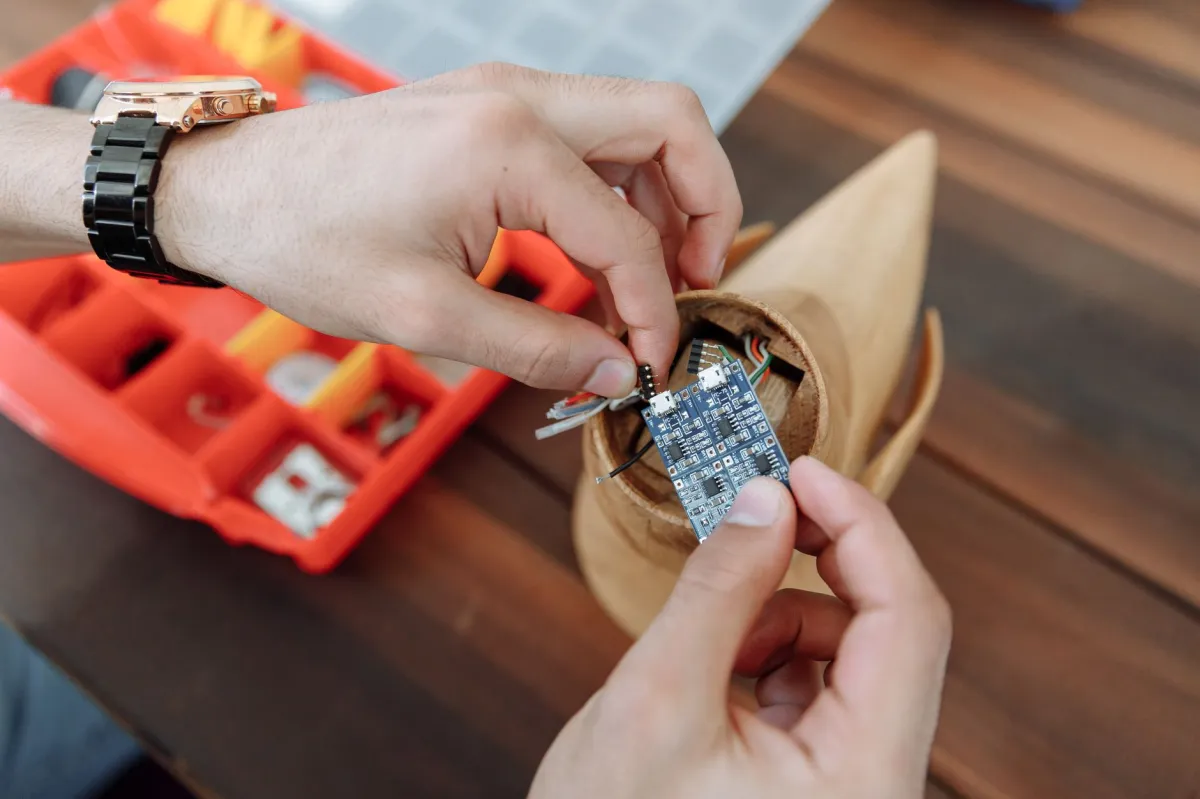 Hands adjusting a microcontroller circuit board, focusing on DIY electronics assembly.