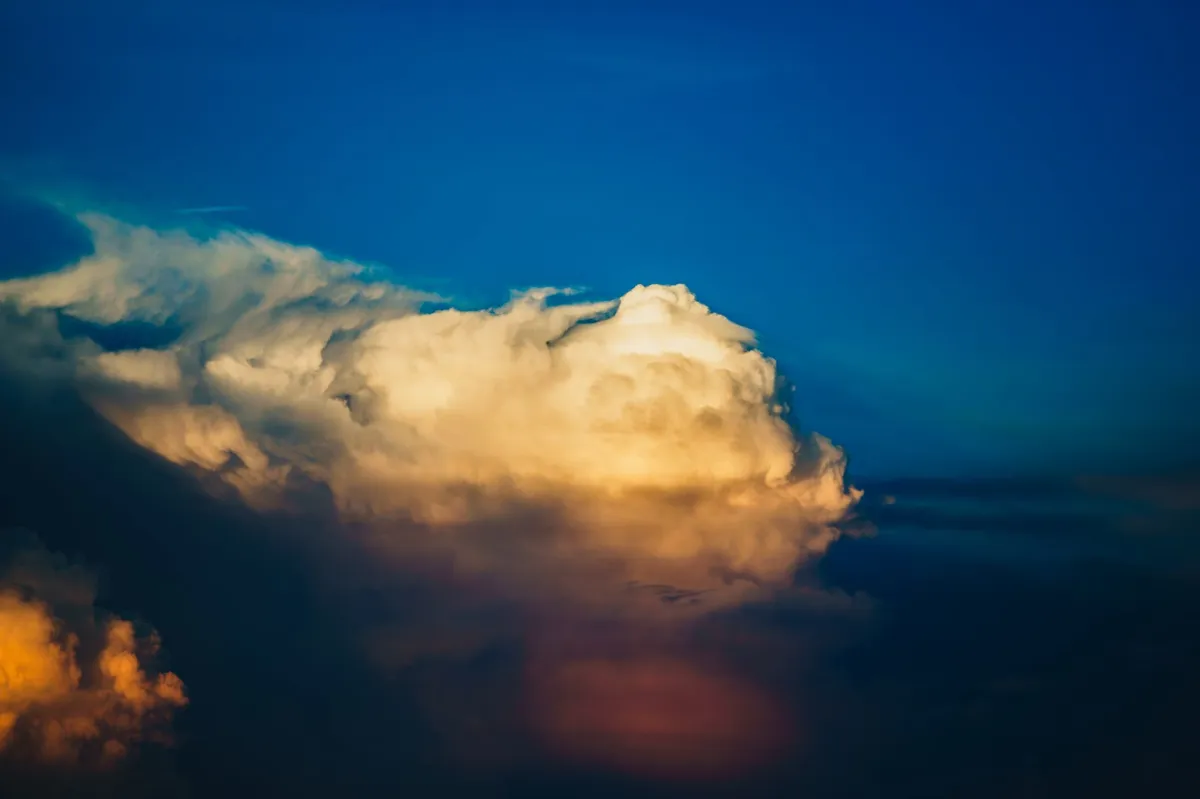 A vivid view of a rising cumulonimbus cloud at sunset against a deep blue sky.