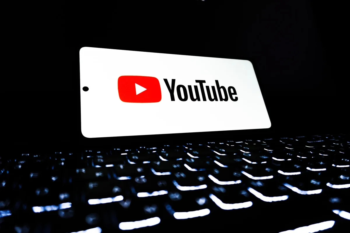 YouTube app icon displayed on a smartphone over an illuminated keyboard