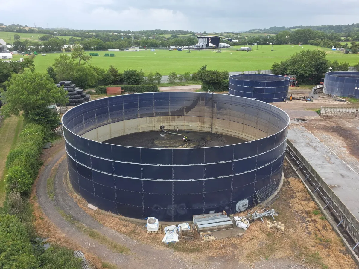 Aerial photo showcasing large industrial water tanks amidst lush countryside landscape under cloudy sky.