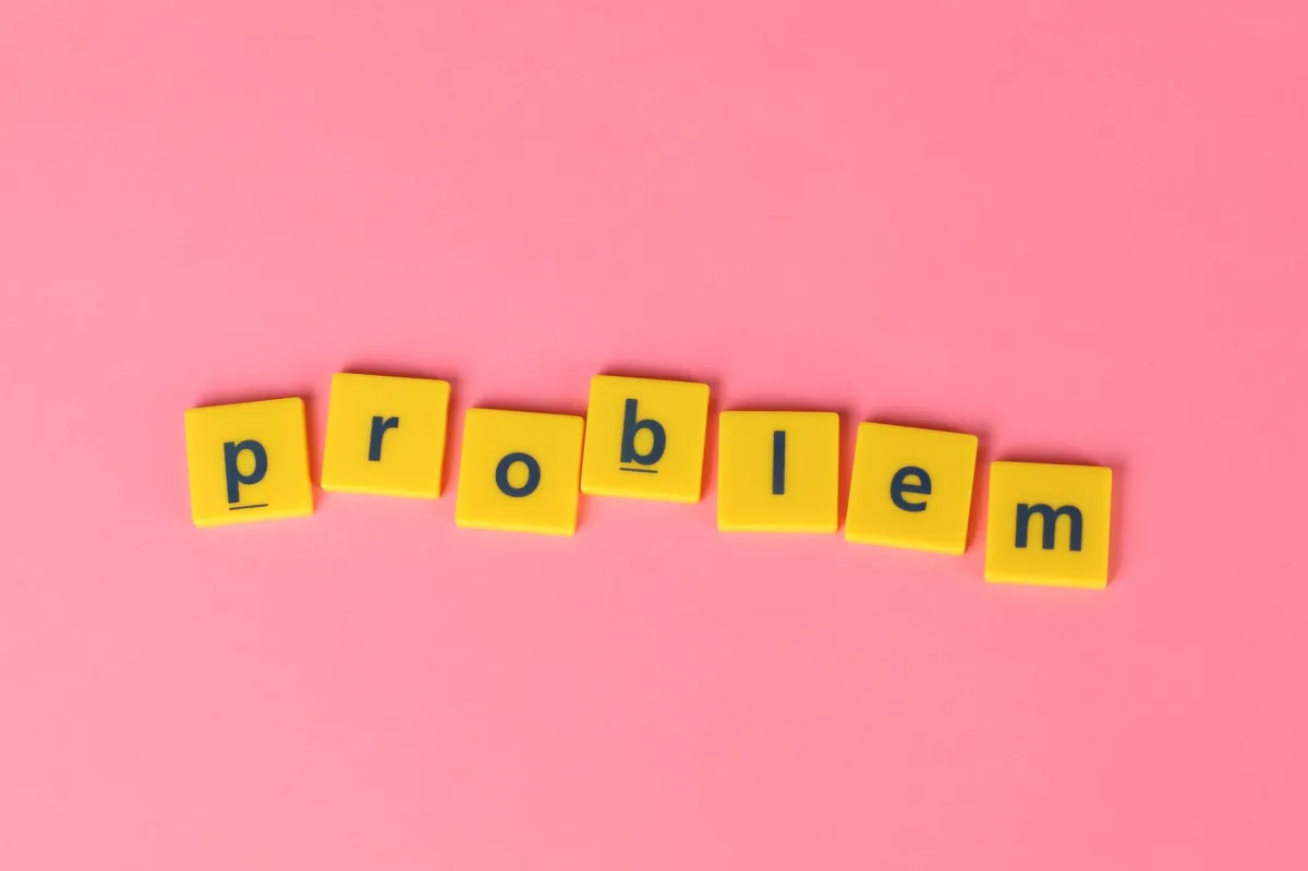 Yellow tiles spell 'problem' on a vibrant pink background, conveying creativity and wordplay.